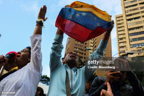 Man holds aloft a Venezuelan flag as people celebrate during a symbolic Venezuelan plebiscite in Caracas, Venezuela, on Sunday, July 16, 2017....