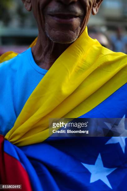 Man wears a Venezuelan flag during a symbolic Venezuelan plebiscite in Caracas, Venezuela, on Sunday, July 16, 2017. Millions of Venezuelans...