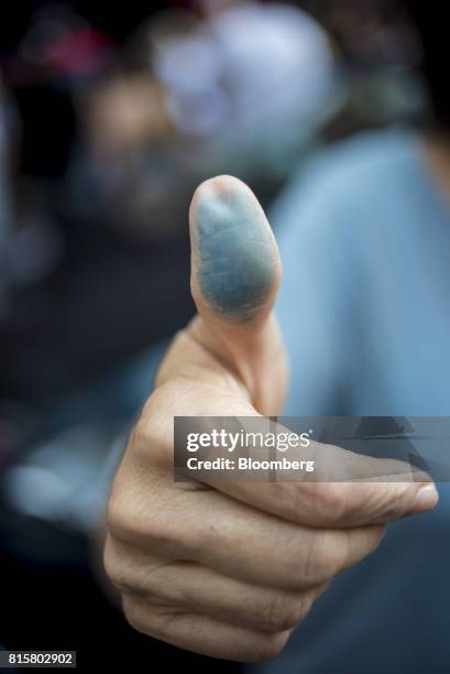 Venezuelan citizen living in the United States shows her thumb imprint after voting during a symbolic plebiscite in New York, U.S., on Sunday, July...