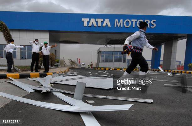 Security guards tries to restrict movements of guests, as sudden cyclonic winds disrupted the inauguration event of Tata Motors plant, causing major...