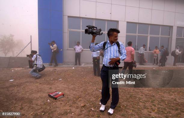 Media person tries to save himself from cyclonic winds at newly inaugurated plant of Tata Motors at Sanand, Gujarat.