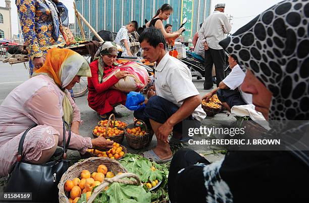 Buyers haggle over apricot prices with a fruit-seller at the Sunday Bazaar in Kashgar on June 15, 2008 in northwest China's Xinjiang Uighur...