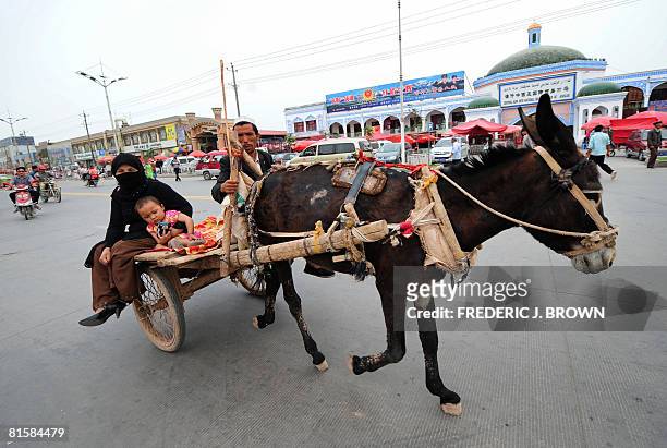 Woman and child get a ride on a donkey cart passing the Sunday Bazaar in Kashgar on June 15, 2008 in northwest China's Xinjiang Uighur Autonomous...