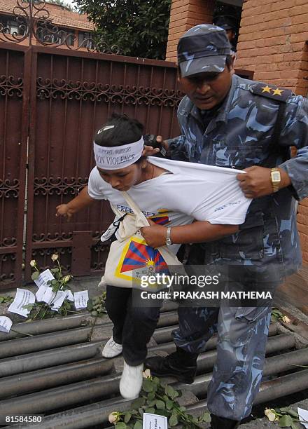 Pro-Tibetan activist is detained by a Nepalese policeman after placing a bunch of white flowers in front the entrance to The United Nations...