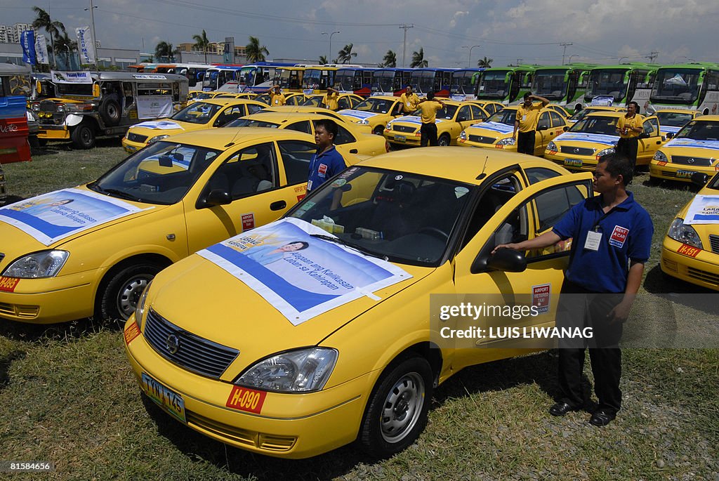 Drivers stand beside modified taxis and