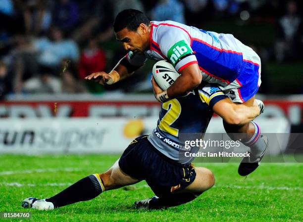 Cooper Vuna of the Knights is tackled by Mark Henry of the Cowboys during the round 14 NRL match between the North Queensland Cowboys and the...