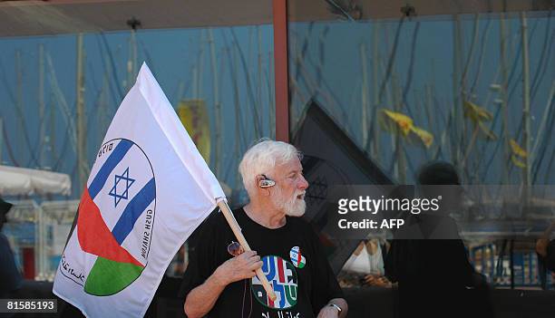 An Israeli left wing activist holds a placard displaying the Israeli and the Palestinian flags during a protest calling for an end of the blockade...