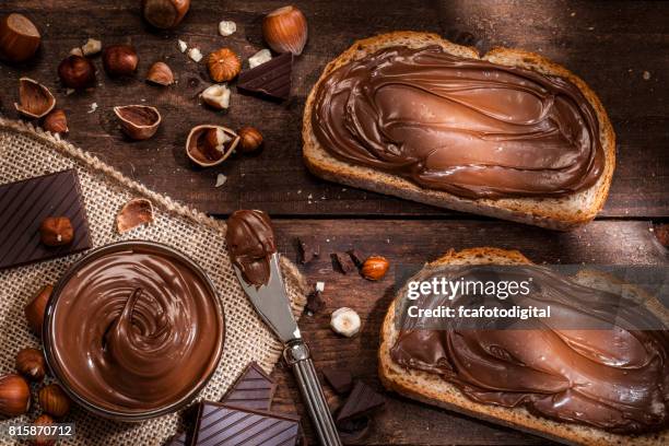 chocolate and hazelnut spread on bread slices shot on rustic wooden table - chocolate spread stock pictures, royalty-free photos & images