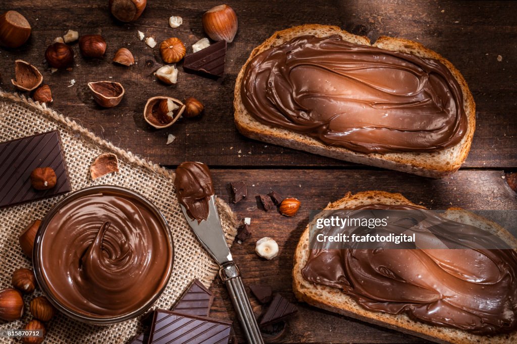 Chocolate and hazelnut spread on bread slices shot on rustic wooden table