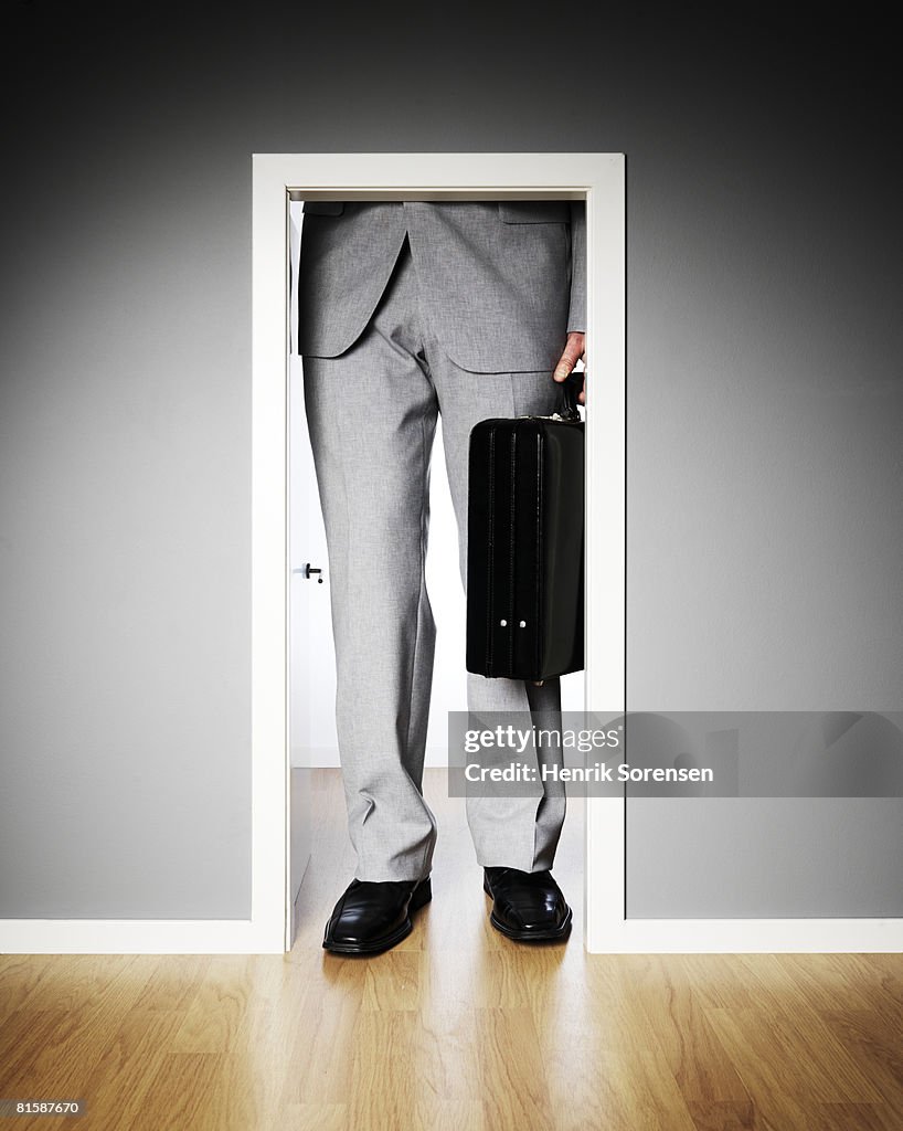 Businessman standing outside a very small door.