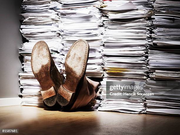 a pair of feet sticking out from under a pile of papers. - overwerkt stockfoto's en -beelden