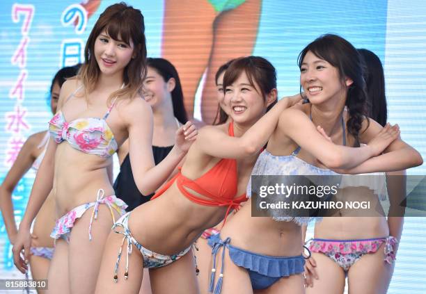 Models wearing new bikinis pose for the media following a promotional flash mob dance performance in Tokyo on July 17, 2017. The event was organized...