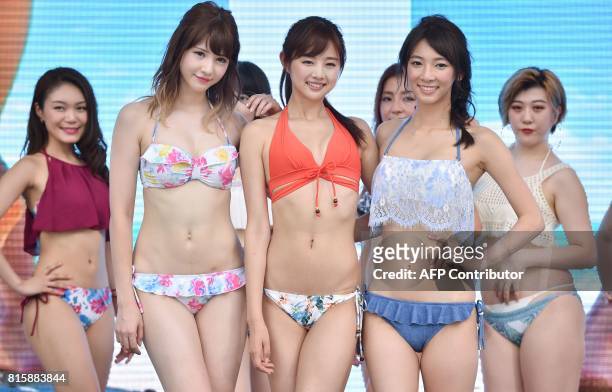 Models wearing new bikinis pose for the media following a promotional flash mob dance performance in Tokyo on July 17, 2017. The event was organized...