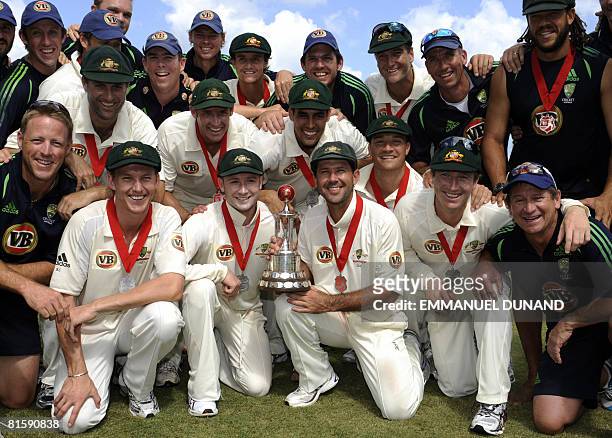 Australian cricket players and team members pose with the Worrell Trophy after their series' victory over the West Indies, at the end of the fifth...