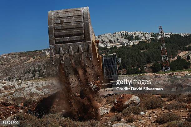 Hydraulic excavator breaks ground for a new section of Israel's separation barrier near the Jewish neighborhood of Ramat Shlomo, on June 16, 2008...