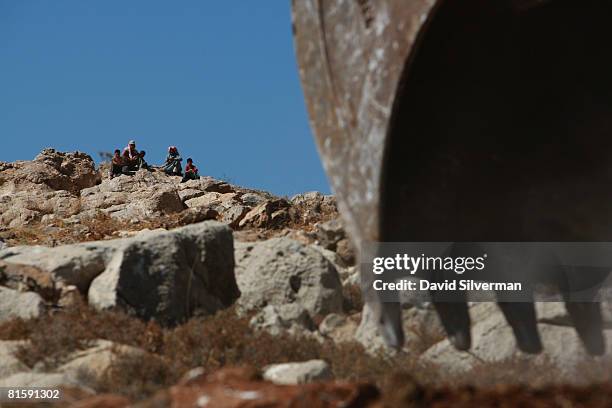 Palestinians watch as a hydraulic excavator breaks ground for a new section of Israel's separation barrier near the Jewish neighborhood of Ramat...