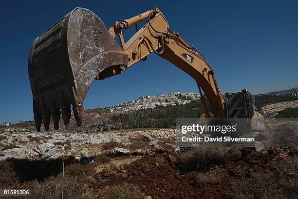 Hydraulic excavator breaks ground for a new section of Israel's separation barrier near the Jewish neighborhood of Ramat Shlomo, on June 16, 2008...
