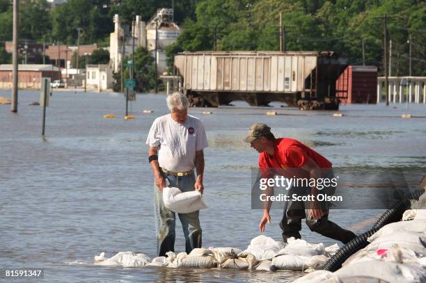 Bryan Schulte and Joe Howell secure a pump hose with sandbags as water from the Mississippi River rises along the riverfront June 16, 2008 in...