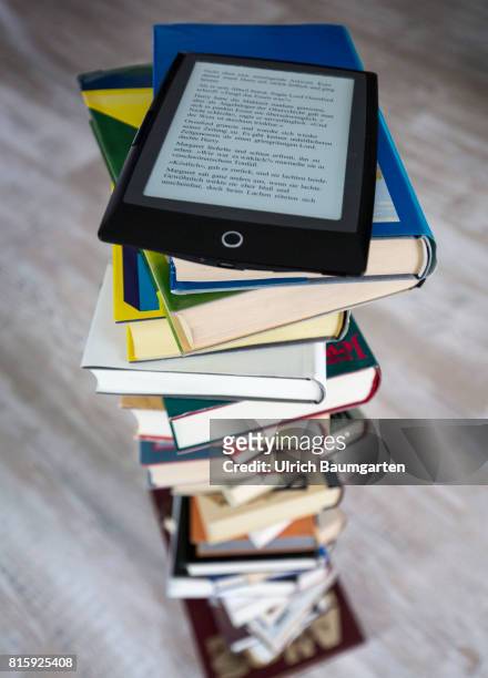 Symbol photo on the topics of literature, reading, eBook, books, leisure, vacation, etc. The photo shows an eBook on stacked books.