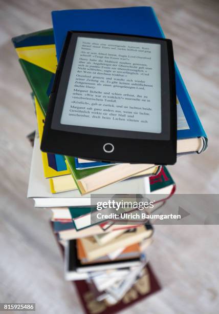 Symbol photo on the topics of literature, reading, eBook, books, leisure, vacation, etc. The photo shows an eBook on stacked books.