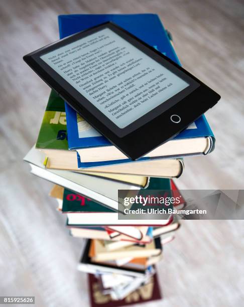 Symbol photo on the topics of literature, reading, eBook, books, leisure, vacation, etc. The photo shows an eBook on stacked books.