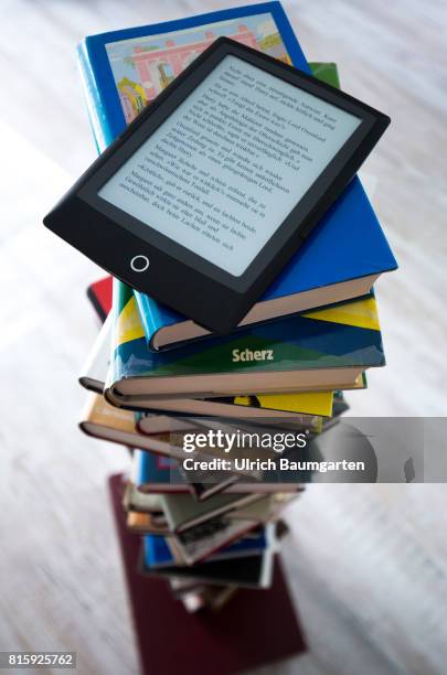 Symbol photo on the topics of literature, reading, eBook, books, leisure, vacation, etc. The photo shows an eBook on stacked books.