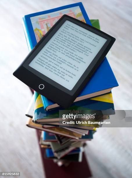 Symbol photo on the topics of literature, reading, eBook, books, leisure, vacation, etc. The photo shows an eBook on stacked books.