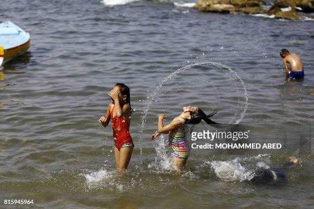 Palestinian girls swim at the beach on a hot day in Gaza City on July 17, 2017. / AFP PHOTO / MOHAMMED ABED