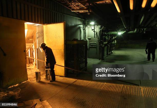 Worker carries a bucket in the steel smelting shop at the Oskol Elektrometallurgical Plant steel mill, operated by Metalloinvest Holding Co., in...