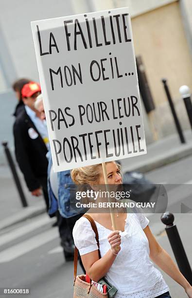 Woman holds a board reading "Bankruptcy, My foot ... Not for their wallet" as she demonstrates as part of a nationwide strike called by the two...