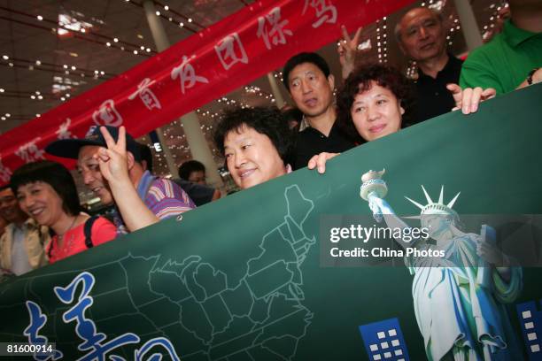 Tourists pose with a billboard printed with the Statue of Liberty at the Beijing Capital International Airport on on June 17, 2008 in Beijing, China....