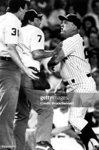 Third base coach Don Zimmer of the New York Yankees is held back by home plate umpire Dave Phillips as Zimmer tries to get at Tim Welke after Welke...