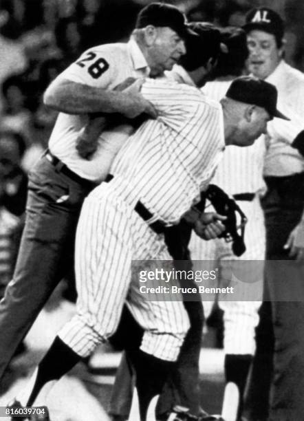 Third base coach Don Zimmer of the New York Yankees is restrained by umpire George Maloney as Zimmer tries to get at Tim Welke after Welke threw...