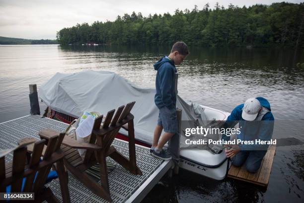 Nathan Kimble, right, and his son, Alex uncover their boat to go count loons on Crescent Lake for a half a hour Saturday morning. Kimble has been...