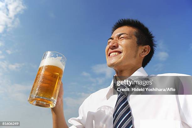 businessman holding a beer - man sipping beer smiling stockfoto's en -beelden