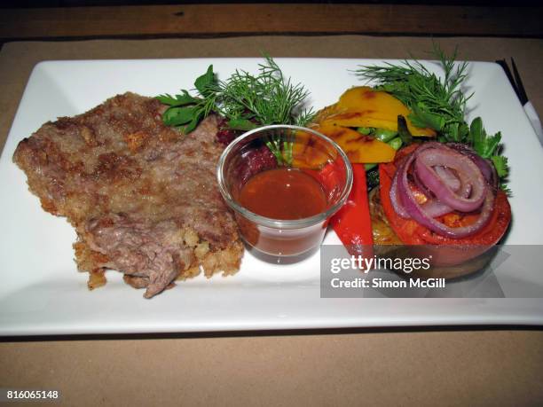 veal schnitzel served with grilled tomato, eggplant, red onion, red and yellow capsicum and a savory sauce - savory sauce 個照片及圖片檔