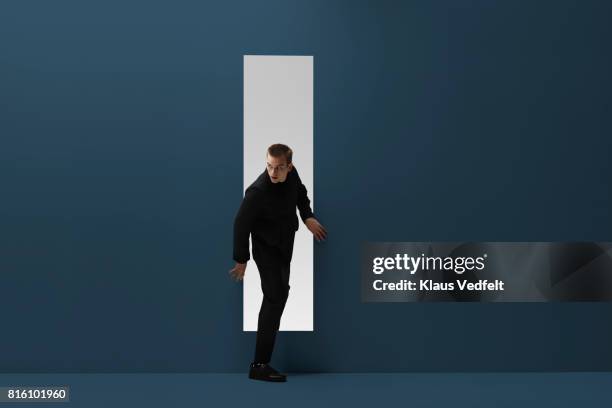 man walking threw rectangular opening in coloured room - regarder à la dérobée photos et images de collection