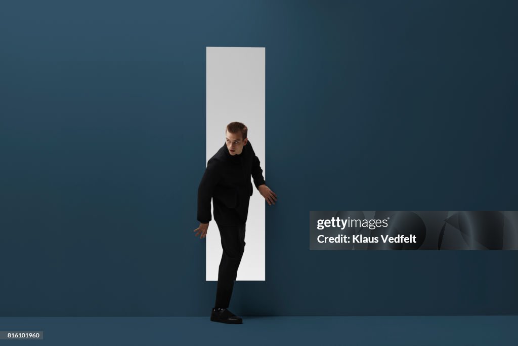 Man walking threw rectangular opening in coloured room