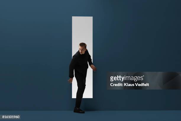 man walking threw rectangular opening in coloured room - suspicion stock pictures, royalty-free photos & images