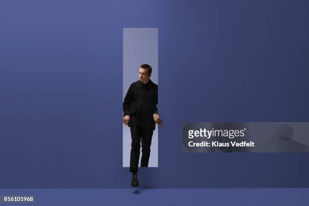 man walking threw rectangular opening in coloured room - aparición conceptos fotografías e imágenes de stock