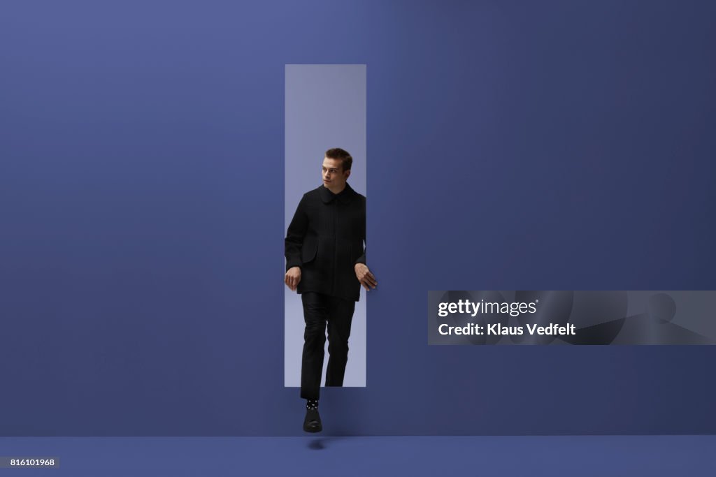 Man walking threw rectangular opening in coloured room