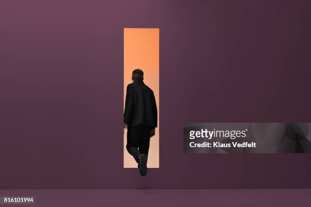 man walking threw rectangular opening in coloured room - vista posteriore foto e immagini stock
