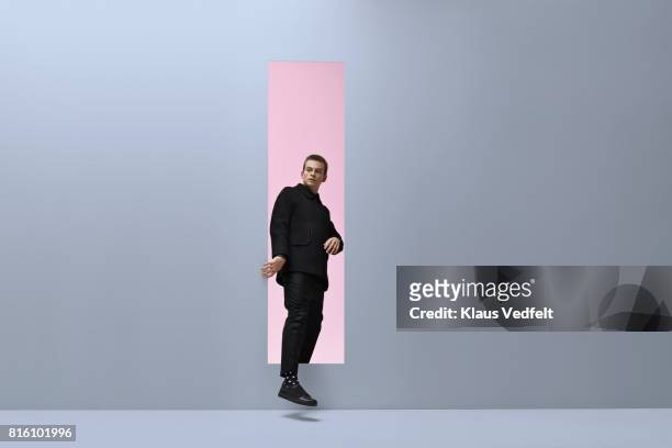 man walking threw rectangular opening in coloured room - appearance foto e immagini stock