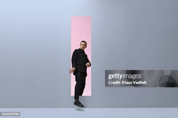 man walking threw rectangular opening in coloured room - hole ストックフォトと画像