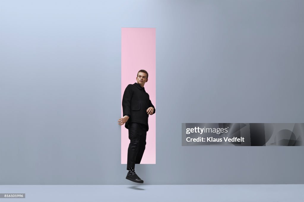 Man walking threw rectangular opening in coloured room