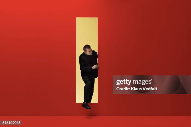 man walking threw rectangular opening in coloured room - recto vestimenta fotografías e imágenes de stock