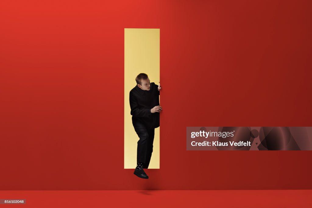 Man walking threw rectangular opening in coloured room