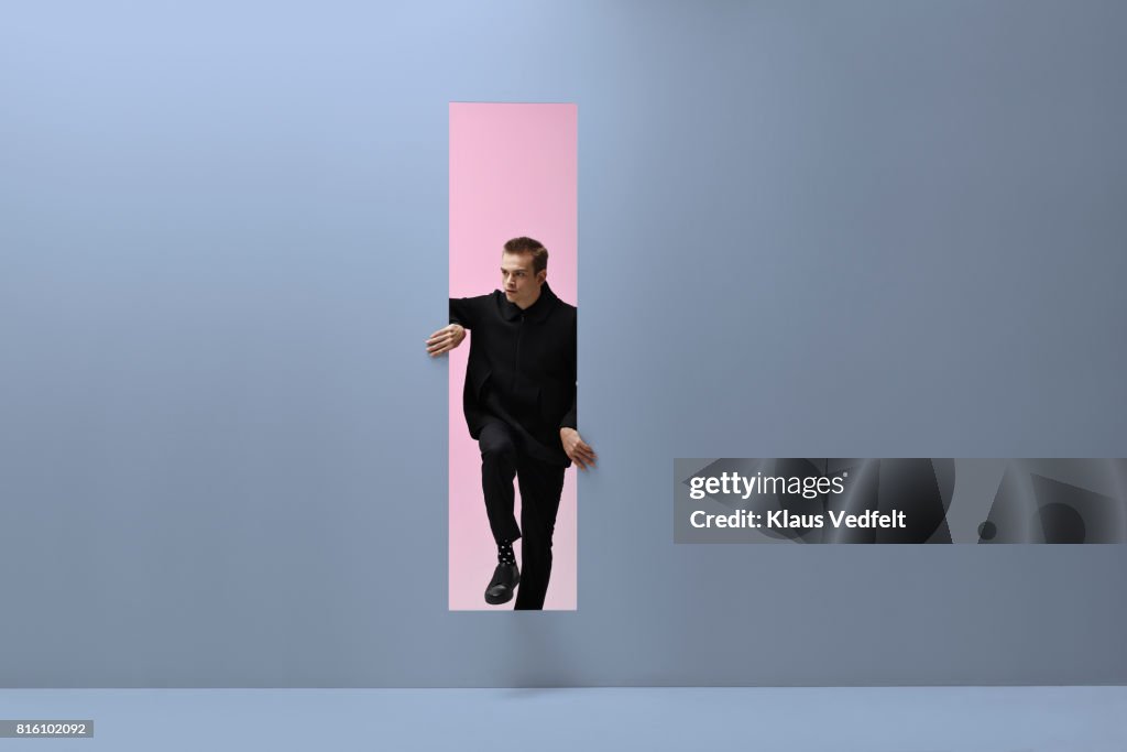 Man walking threw rectangular opening in coloured room