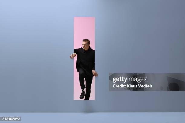 man walking threw rectangular opening in coloured room - stepping stock pictures, royalty-free photos & images