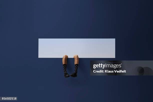 feet of businessman, sticking out rectangular opening in coloured wall - change socks stockfoto's en -beelden